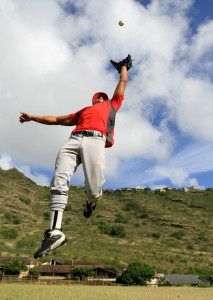 Baseball player jumps high to catch a fly ball